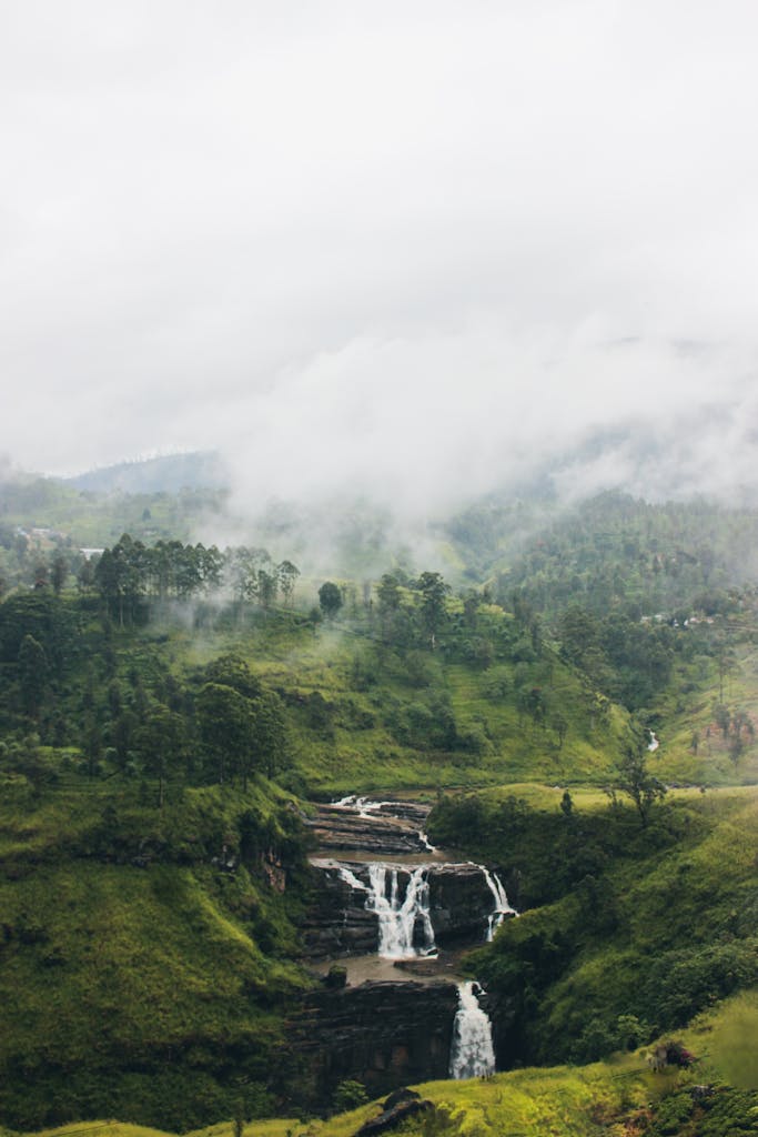 A breathtaking view of scenic waterfalls amidst misty hills in Thalawkele, Sri Lanka.