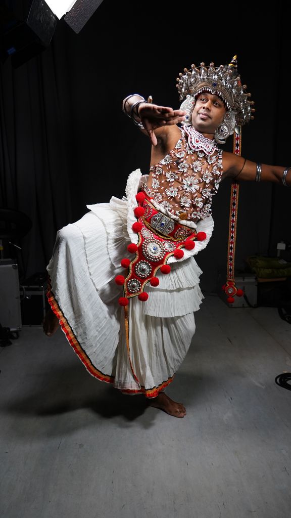 Vibrant traditional dancer in ornate costume performing indoors with elegant grace.